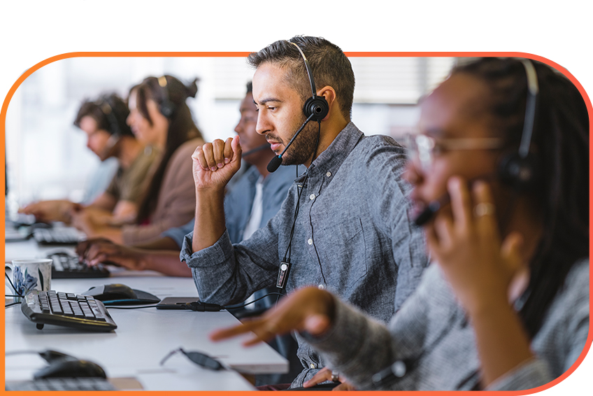 Diverse group of customer service representatives wearing headsets and working at computers.