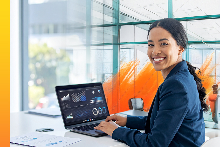 Woman working on her computer smiles toward the camera.