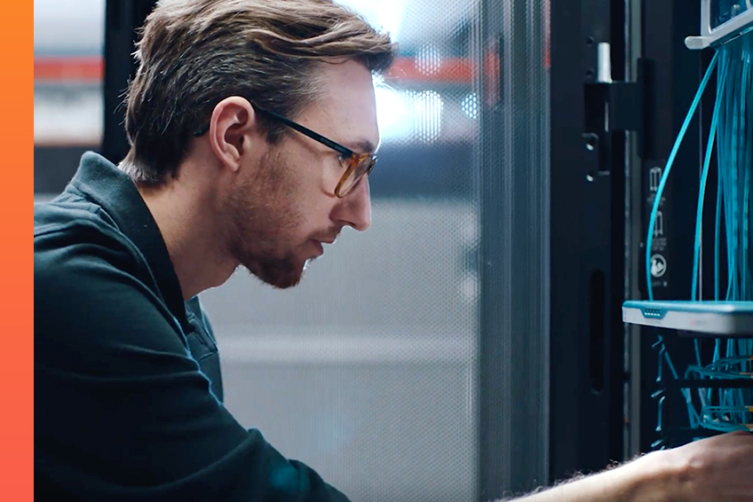 A person works on a server rack and handles network cables.