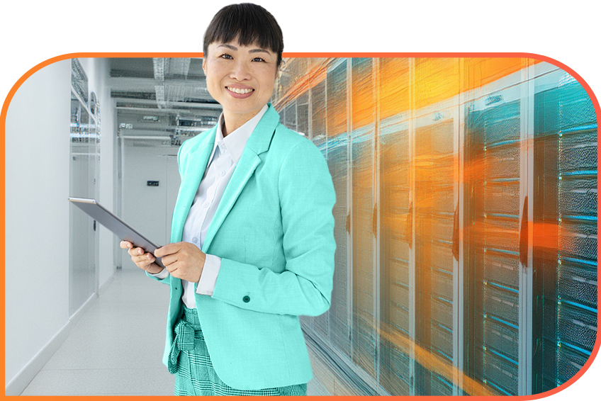 Businessperson in a teal blazer stands in a data center and holds a tablet.